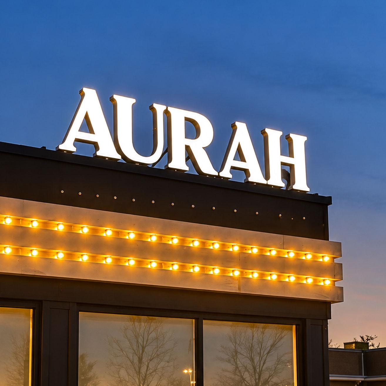 Illuminated AURAH channel letters on a rooftop at dusk, made by Madix
