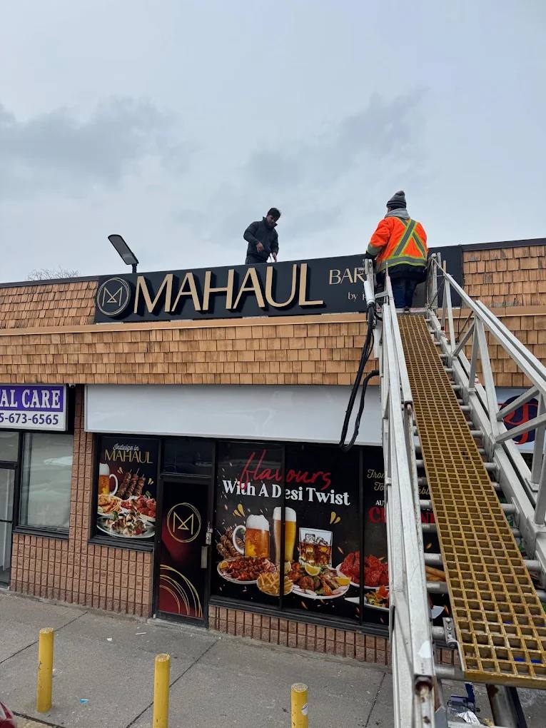 Madix installers mounting the Mahaul storefront sign above window graphics