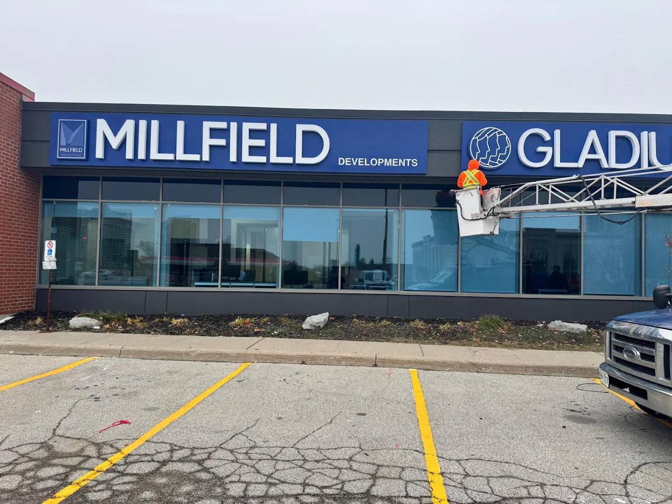 Madix installer in a bucket truck mounting a storefront sign